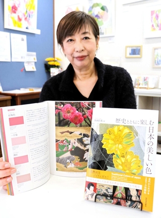 日本の伝統色を紹介する著書を手にした魚田昌美さん＝豊岡市城崎町湯島、ギャラリー２６２６キノサキ