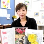 日本の伝統色を紹介する著書を手にした魚田昌美さん＝豊岡市城崎町湯島、ギャラリー２６２６キノサキ