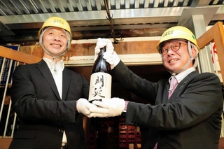 蔵出しした純米酒「明延」を掲げる（左から）山陽盃酒造の壺阪雄一専務と大林賢一養父市長＝養父市大屋町明延