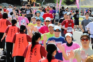 村岡高校生とハイタッチして出発するランナーたち＝香美町小代区野間谷