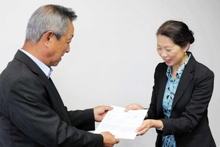 高校での外国人生徒特別枠の導入に向け、請願書を提出するにほんご豊岡あいうえおの岸田尚子事務局長（右）＝豊岡市役所