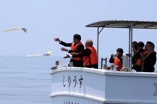 海防艦２隻が沈む海に卒塔婆を投げ入れる参列者たち＝香住沖