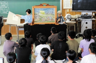 子どもたちに満州開拓団の紙芝居を読み聞かせる「語り継ぐ会」の語り手たち＝豊岡市但東町出合市場