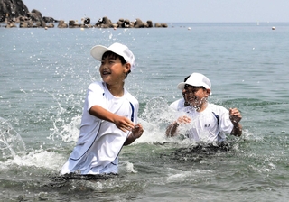 水しぶきを上げながら海を楽しむ児童＝豊岡市竹野町竹野