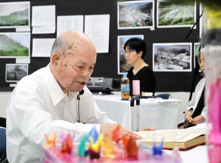殉難者３４６人の名前を読み上げる山下幸雄さん＝豊岡市但東町久畑