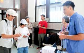 豊岡市街地や復興建築群などを巡る謎解きツアーのモニターツアーが実施され、地図などを受け取る参加者たち＝豊岡市中央町