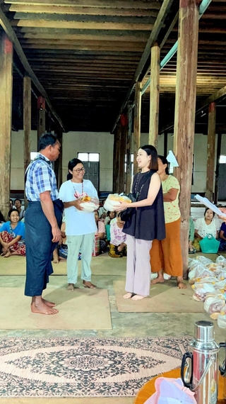 講堂に集まった住民に食糧を配る田中かのんさん（右）＝８月３日、ミャンマー・ニャウンシェのインレー湖（田中さん提供）