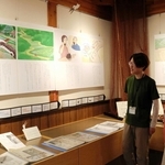 コウノトリの保護増殖に尽力した松島興治郎さんの歩みを紹介する紙芝居。物語を手がけた山下美登理さん（右）、イラストを担当した桐島杏莉さん＝豊岡市祥雲寺