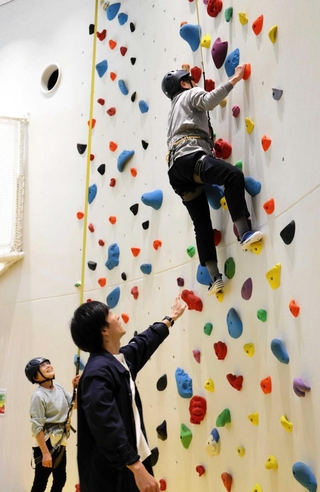スタッフの指導を受けてクライミングに挑む山根久男さん＝豊岡市日高町伊府