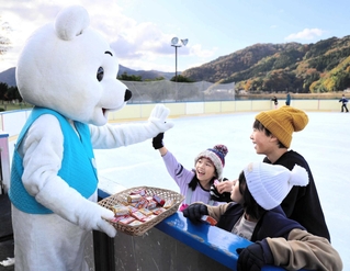 開業したスケートリンクで、マスコット「シロクマくん」からお菓子を受け取る子どもたち＝豊岡市小島
