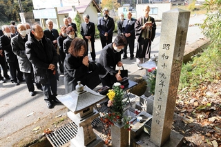 事故現場の碑に手を合わせる参列者たち＝養父市出合