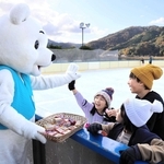 開業したスケートリンクで、マスコット「シロクマくん」からお菓子を受け取る子どもたち＝豊岡市小島