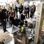事故現場の碑に手を合わせる参列者たち＝養父市出合