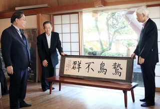石破茂前首相の揮毫を紹介する谷公一衆院議員（左）や斎藤隆夫顕彰会の理事ら＝豊岡市出石町中村