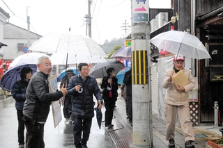 高橋雅樹さん（左から２人目）の案内で、りくゆかりのまち並みを歩く参加者＝豊岡市京町