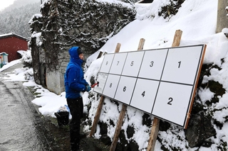 雪が降る中、衆院選のポスター掲示板を設置する男性＝新温泉町岸田