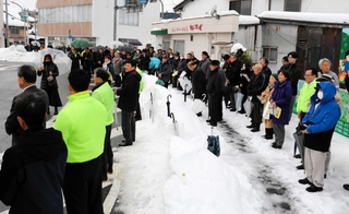 雪が積もった豊岡市内で立候補者の主張を聞く支持者ら＝同市泉町