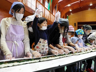 「せーの」のかけ声ですしを巻く参加者＝豊岡市竹野町轟