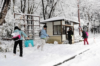 雪遊びをしながらバスを待つタイからの観光客たち＝豊岡市日高町栗栖野