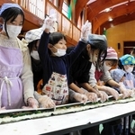 「せーの」のかけ声ですしを巻く参加者＝豊岡市竹野町轟