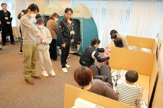 簡易トイレや段ボールベッドなどの使用を体験する参加者ら＝養父市八鹿町八鹿