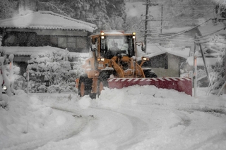 車道に降り積もった大量の雪をかきのける除雪車＝２０２５年１２月２６日、養父市葛畑（撮影・吉田みなみ）