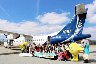 トキエアへの搭乗を前に、記念撮影に収まる但馬発ツアー参加者たち＝豊岡市岩井