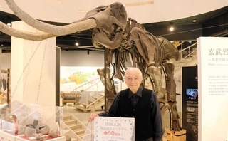 玄武洞ミュージアムが創業から５０周年を迎え、記念パネルや化石を紹介する田中榮一館長＝豊岡市赤石