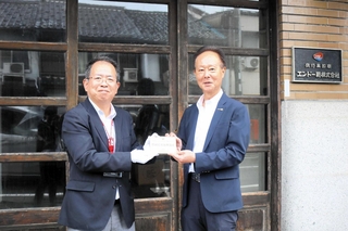 豊岡震災復興遺産のプレートを受け取るエンドー鞄の遠藤玄一郎相談役（右）＝豊岡市元町