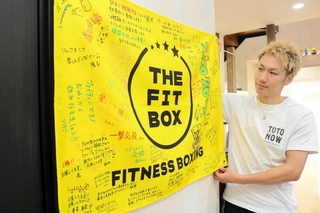 長谷川穂積さん主催のボクシング大会に出場する際、ジムの利用者らが贈ってくれた旗と寄せ書きを前にする立川惇貴さん＝豊岡市正法寺
