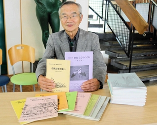 第５１回で活動を終える「但馬文学のつどい」について、過去の記録集を手に歩みを振り返る企画運営委員会の橋岡進一委員長＝豊岡市妙楽寺