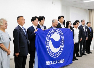 「但馬ユネスコ協会」が設立され、旗を前に記念撮影に臨む役員ら＝豊岡市中央町