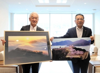 朝来市に写真を寄贈した谷吉將さん（左）と受け取った藤岡勇市長＝同市役所（同市提供）