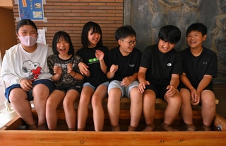 学校で源泉かけ流しの足湯に入る子どもたち＝温泉小学校