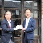 豊岡震災復興遺産のプレートを受け取るエンドー鞄の遠藤玄一郎相談役（右）＝豊岡市元町