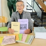 第５１回で活動を終える「但馬文学のつどい」について、過去の記録集を手に歩みを振り返る企画運営委員会の橋岡進一委員長＝豊岡市妙楽寺