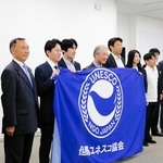 「但馬ユネスコ協会」が設立され、旗を前に記念撮影に臨む役員ら＝豊岡市中央町