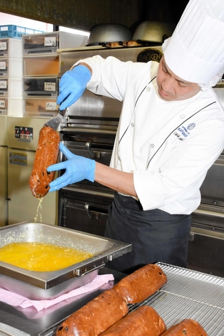焼き上がったシュトーレンを溶かしバターに漬ける＝カタシマ本社工房