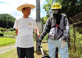制作したかかしと並ぶ納座区長の安保衛さん＝朝来市納座