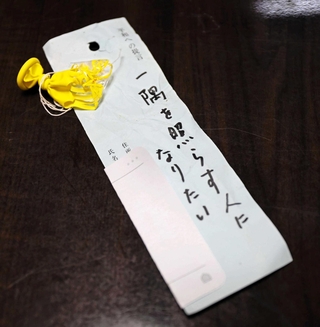 割れた黄色い風船には、手書きで「一隅を照らす人になりたい」と記された短冊がつながっていた＝朝来市生野町新町