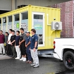 移動式ランドリーの前で出発のあいさつをする関係者ら＝養父市養父市場