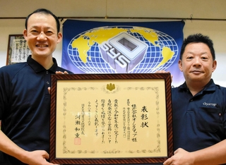 国土地理院長表彰を受けたオーシスマップの魚本崇社長（右）と羽渕秀樹画像計測課長＝養父市八鹿町宿南