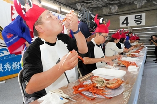 香住ガニ食べ方上手選手権で、カニを頰張る参加者＝香美町香住区若松
