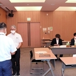 委員長に選ばれ、春名常洋管理者（手前）から諮問書を手渡される石田岳史教授＝公立八鹿病院