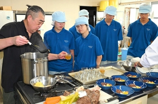 煮込んだ肉や野菜を取り分け、ブイヨンをカップに注ぐ石田克己さん（左端）＝香住高校