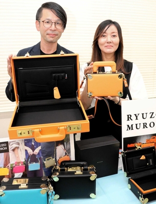 「アクティラビック」のアタッシェケースを手にする福井良祐さん（左）と妻の桃子さん＝豊岡市日高町袮布