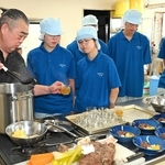 煮込んだ肉や野菜を取り分け、ブイヨンをカップに注ぐ石田克己さん（左端）＝香住高校