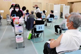 問診後は左腕を出して椅子に座り、接種の順番を待つ＝丹波市立看護専門学校体育館
