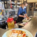 キッチンで料理する居相さん。手前は、丹波鶏や地元の野菜を生かしたスパイスカレー＝丹波篠山市立町