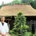 茅葺き屋根の葺き替えを終えた建物の前に立つ「いわや」の店主・岩本和也さん＝丹波篠山市火打岩